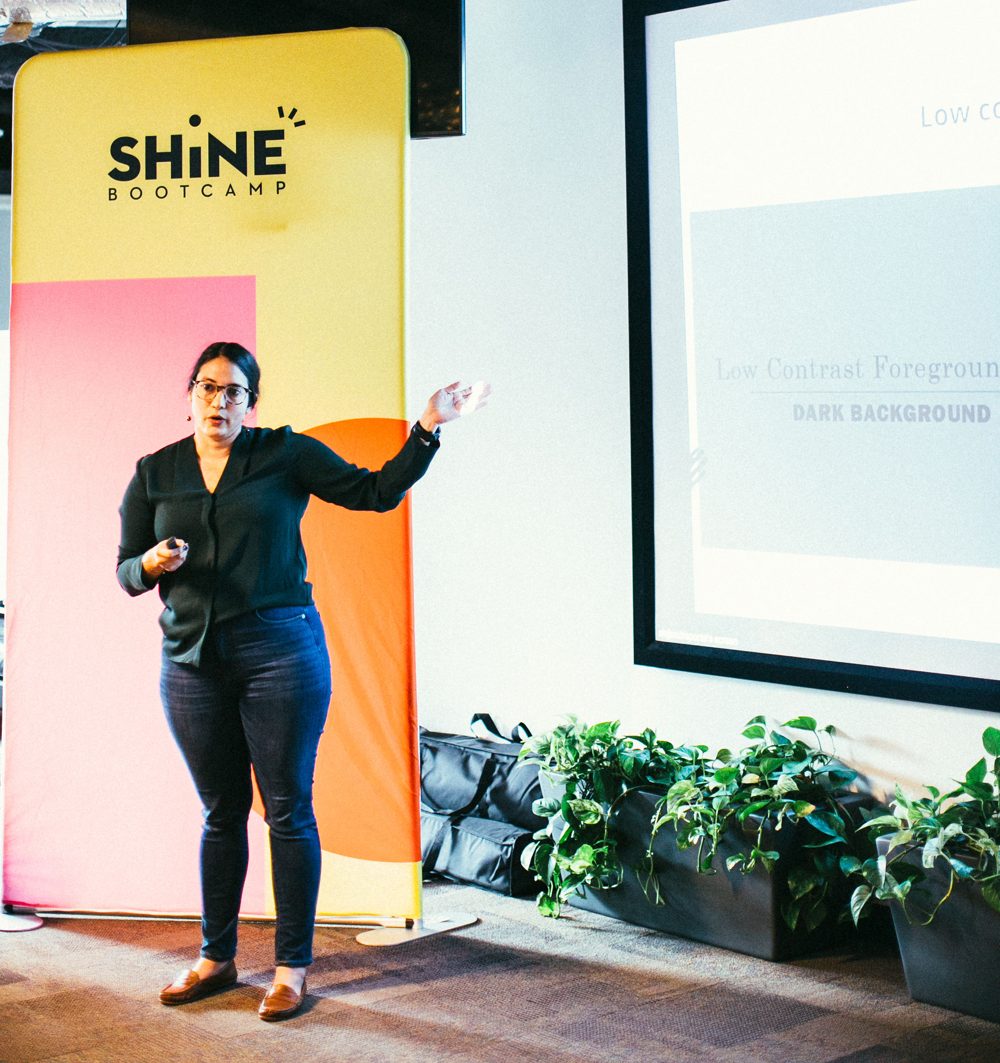 Ale speaking on stage at a Shine Bootcamp event
