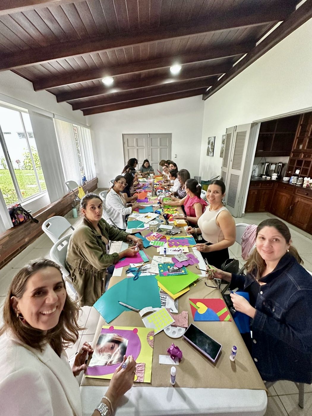 Women making collages around a long table during the Healing your inner child through art workshop